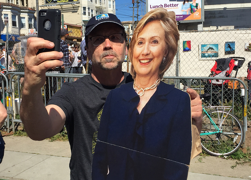 A festival goer snaps a selfie with candidate Hillary Clinton