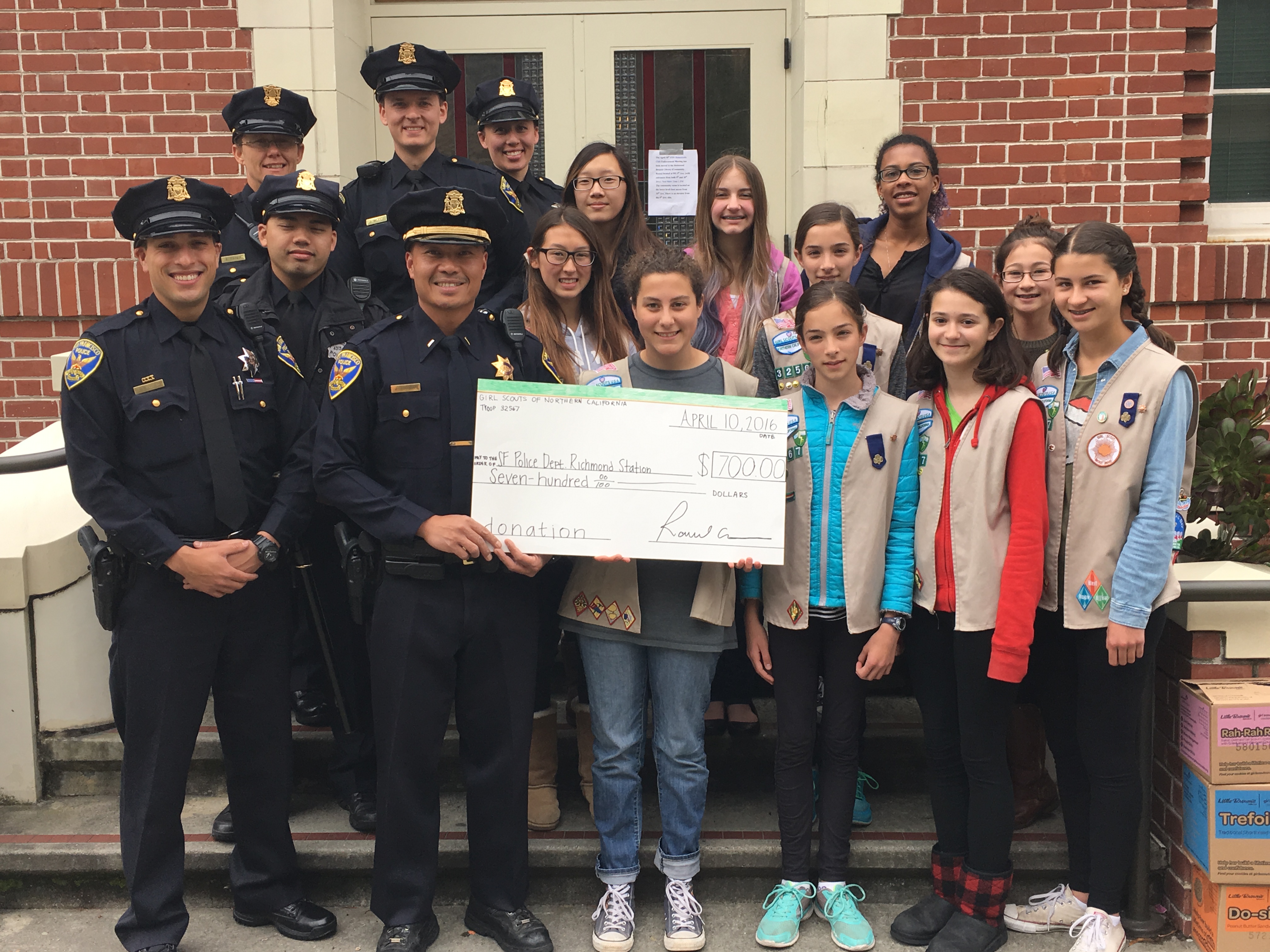 Members of Girl Scout Cadette and Senior Troop #32567 present a $700 check to the Richmond District police station