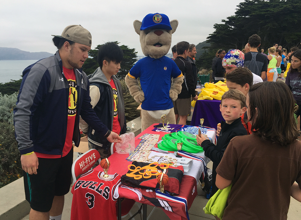 The team from Hi-Five Sports pass out prizes to Mile Rock Challenge finishers with Murphy, their mascot.